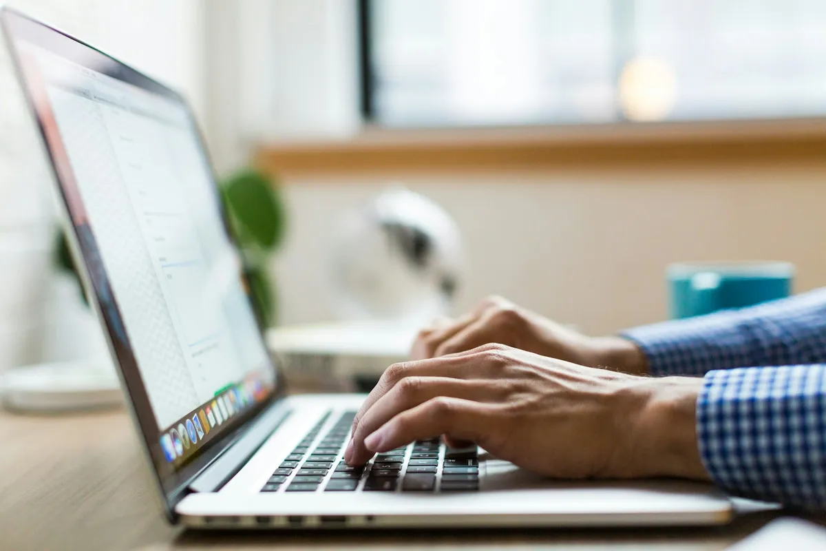 Hands typing on a laptop at a desk