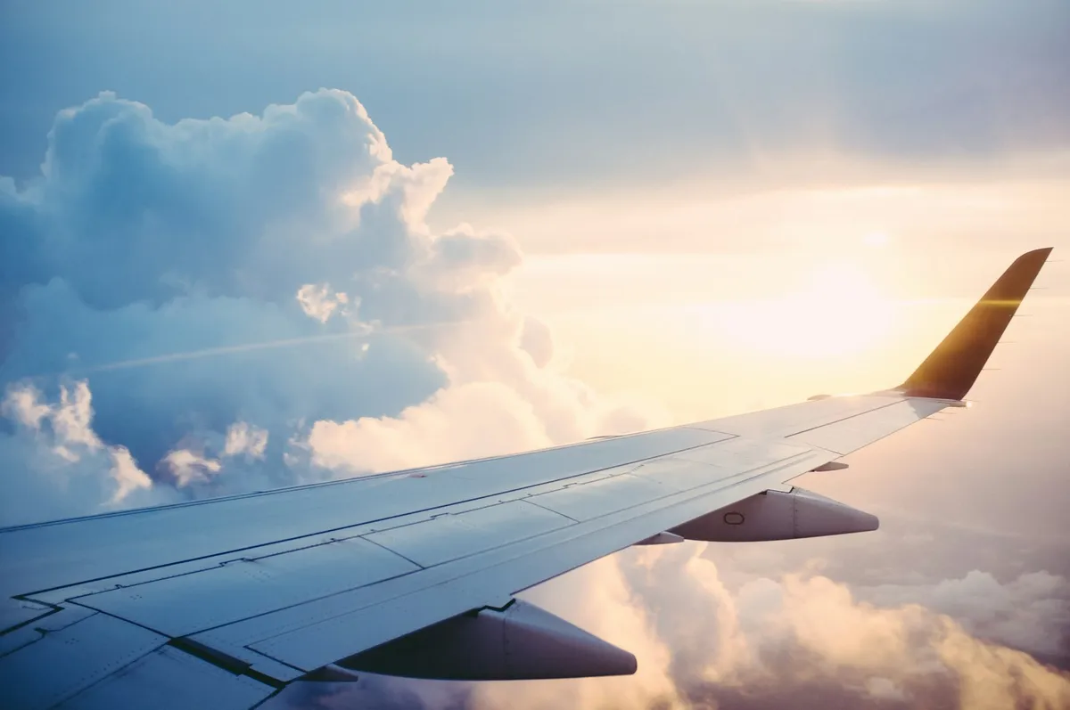 Airplane wing over clouds while traveling